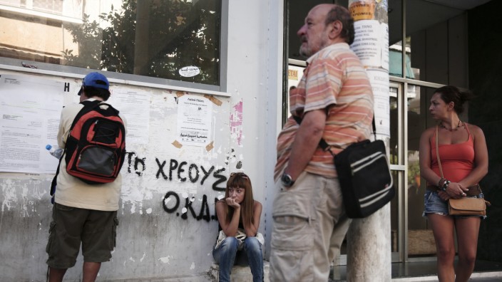 People wait outside a Greek Manpower Employment Organisation office at Kalithea suburb in Athens