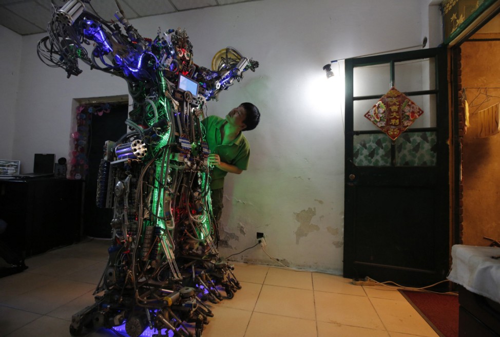 Chinese inventor Tao checks his self-made humanoid robot during a demonstration at his house in Beijing