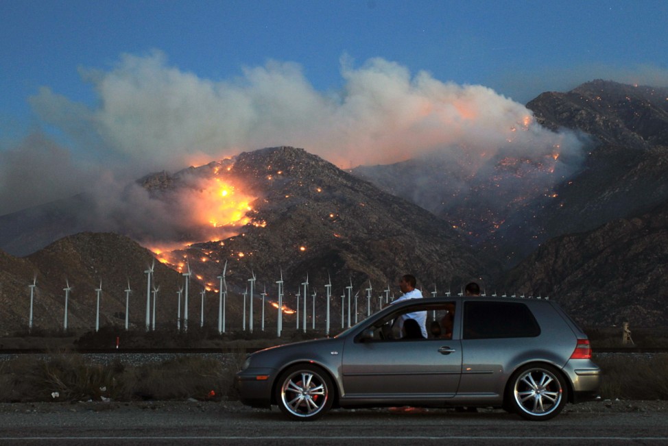 Motorists stop to watch, as fire spreads up north side of San Jacinto Mountains near wind turbines at Silver Fire east of Banning