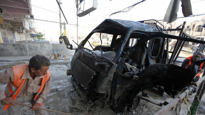 Workers clean up the site of a car bomb attack in Baghdad