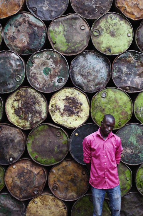 Steel barrel vendor Lassiney Diarra poses for a picture in front of barrels in Bamako