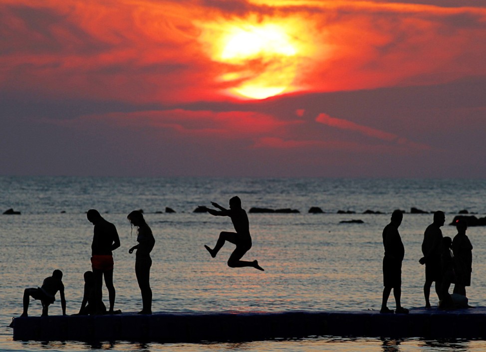 Boy is silhouetted as he jumps into the sea at a beach in the city of Durres