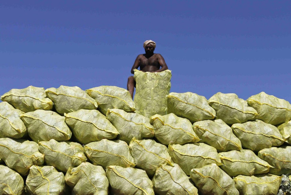 A labourer unloads bags filled with cabbage from a supply truck at a vegetable wholesale market in Chennai