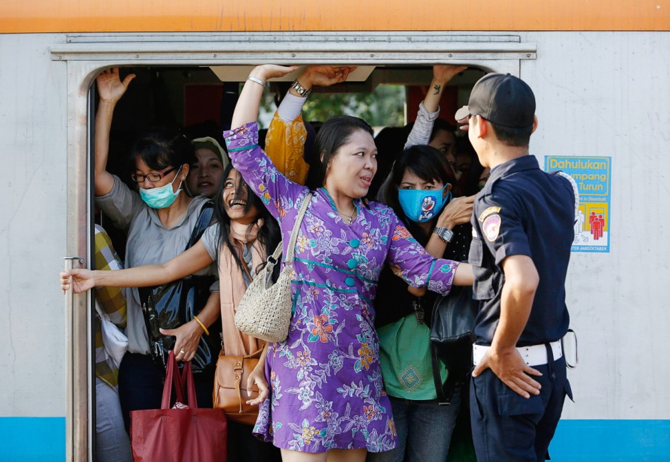 Women push themselves into a train carriage at Sudimara train station on the outskirts of Jakarta