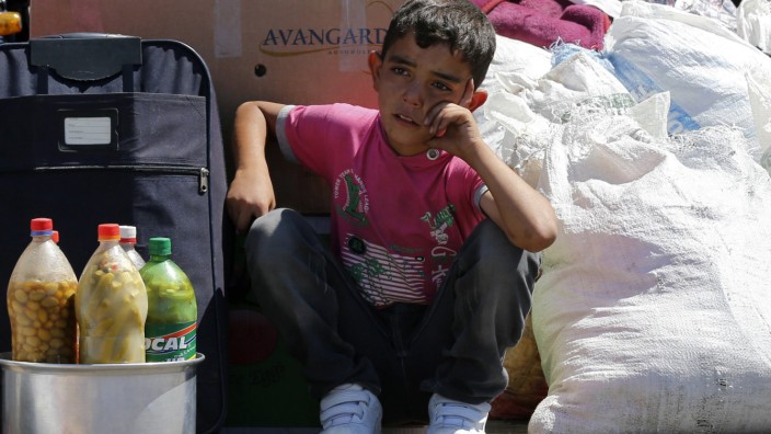 A Syrian boy sits beside his family's belongings as they wait for a vehicle to pick them up after entering Turkey from the Turkish Cilvegozu border gate, located opposite the Syrian commercial crossing point Bab al-Hawa, in Reyhanli, Hatay province