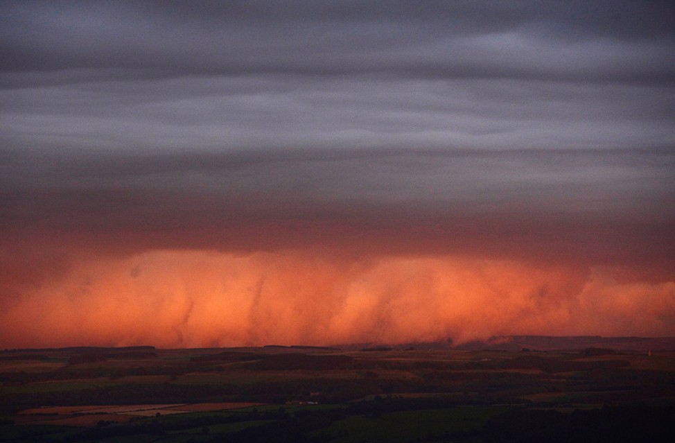 Rain clouds are lit by the setting sun, looking south from Hadrian's Wall near Hexham in northern England