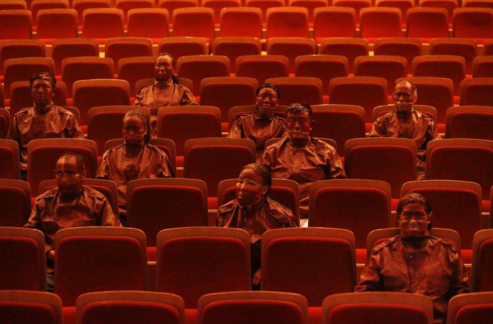 Artist Liu Bolin and other participants are painted as part of a project to make themselves look exactly the same as the seats in Beijing