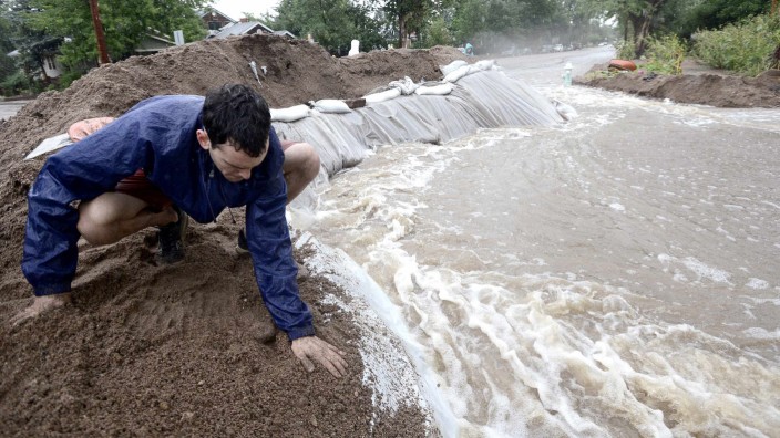 Erez Shani packs down soil at the top of a berm that is redirecting water as heavy rains cause flooding to rise in Boulder, Colorado