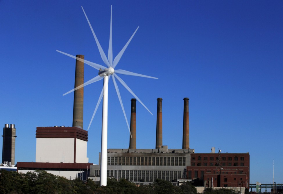 A Massachusetts Water Resources Authority wind turbine turns in front of a 1951 megawatt fossil fuel power plant in Charlestown