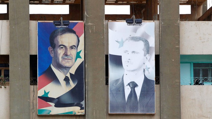 Pictures of Syria's President Assad and his father hang from a government building in Deraa