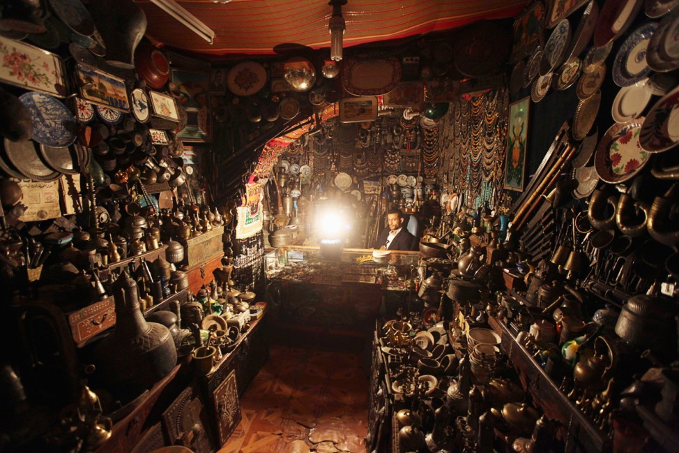 An antiques seller waits by a lantern for customers in his shop during a blackout in Sanaa