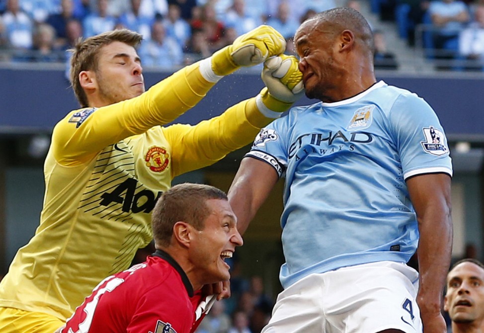 Manchester City's Kompany gets hit in his face as he is challenged by Manchester United's David de Gea during their English Premier League soccer match in Manchester