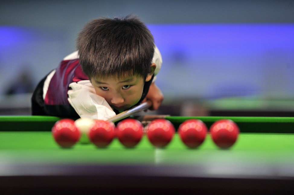 Three-year-old Wang practises before playing snooker with seven-time World Championship winner Hendry in Beijing