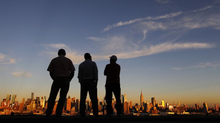 People watch the sun set over New York from a park in Weehawken, New Jersey