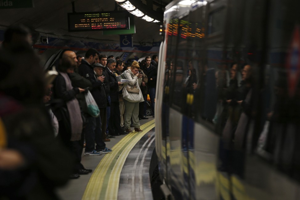A passenger retouches her make-up as she waits on the platform during a morning rush-hour strike by metro workers in Madrid