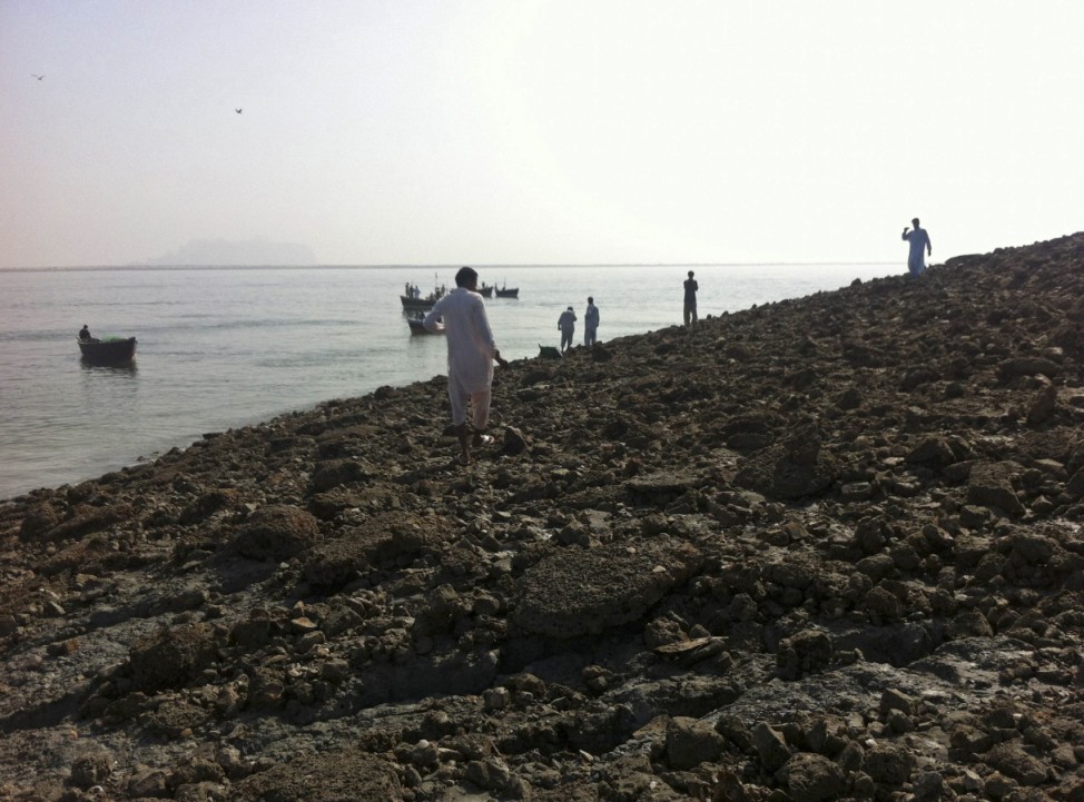 People walk on an island that rose from the sea following an earthquake off Pakistan's Gwadar coastline in the Arabian Sea