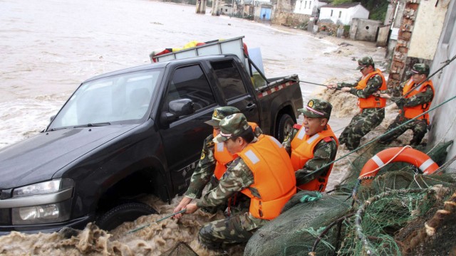 Paramilitary policemen pull up a vehicle overturned by a storm surge near the coastline, under the influence of Typhoon Fitow in Yuhuan