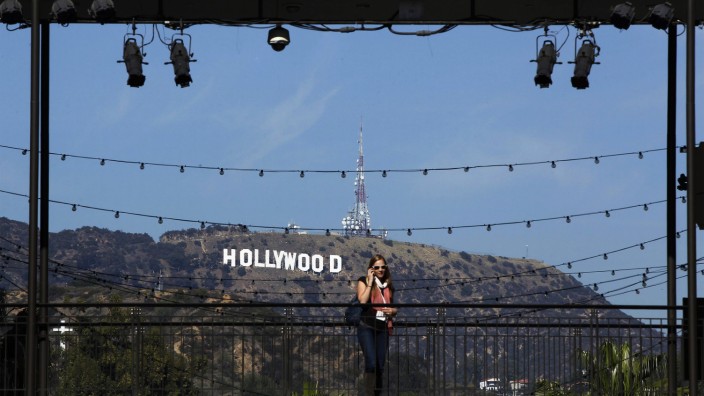 A woman talks on her cellular phone in front of the Hollywood sign prior to the 84th Academy Awards in Hollywood, California