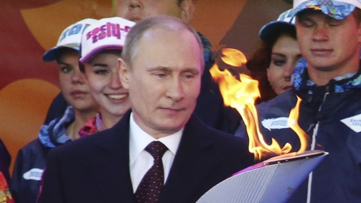 Russian President Putin holds a lighted Olympic torch during a ceremony to mark the start of the Sochi 2014 Winter Olympic torch relay in Moscow