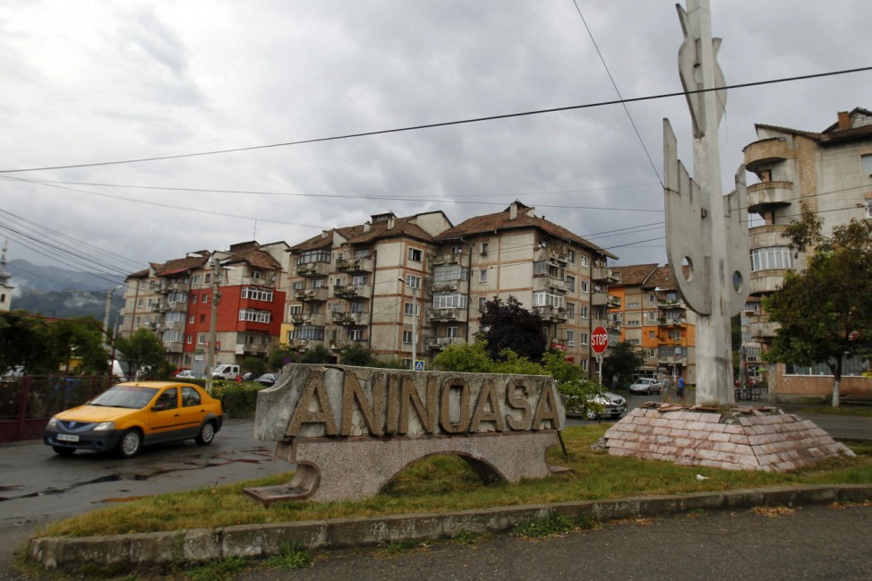 A car drives past a town sign at a road intersection in Aninoasa, west of Bucharest