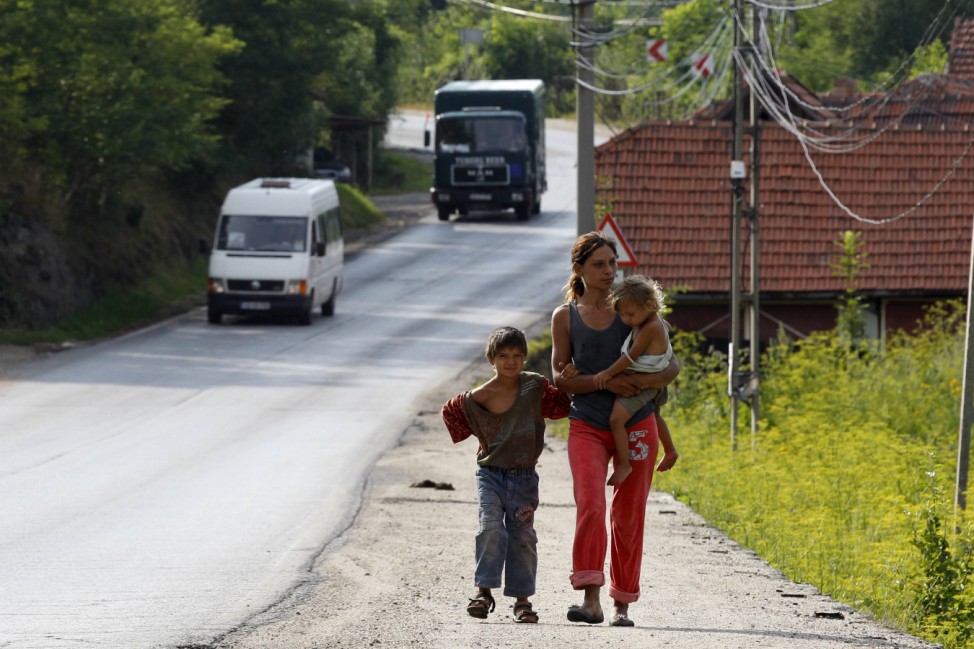 A woman walks with children along a road in Aninoasa, west of Bucharest