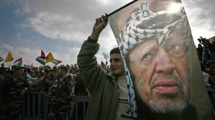 File photo of a Palestinian holding a banner depicting Arafat during a rally in Ramallah