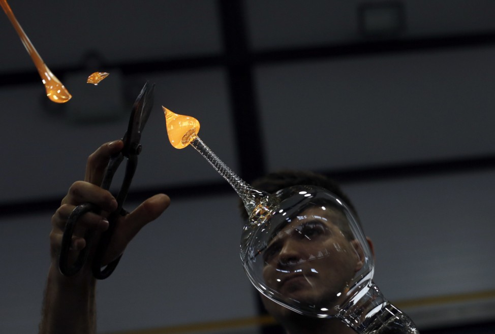 A master glassmaker adds fused material to form the base of a handmade gin-tonic glass at Royal Crystal Factory in Spain