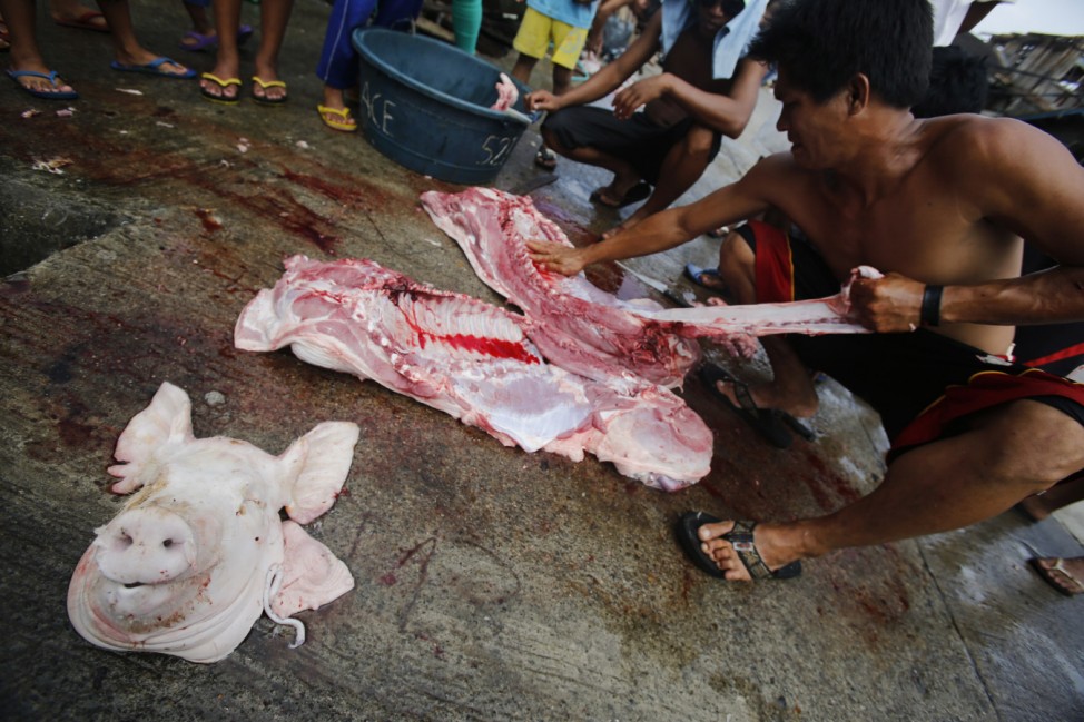 A butcher takes apart a pig that he has just killed in one of the main streets of the central Philippine town of Palo