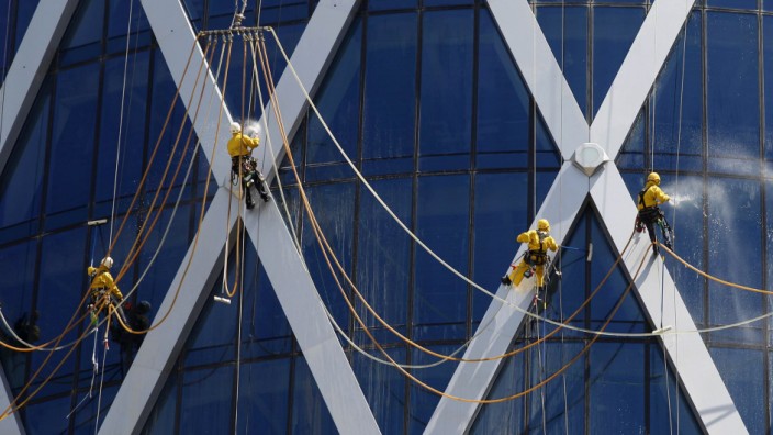 Workers suspended on ropes clean the glass windows of the Tornado tower in Doha