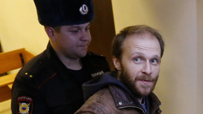Photographer Denis Sinyakov is escorted during a break in a court session before the announcement of the verdict in St. Petersburg