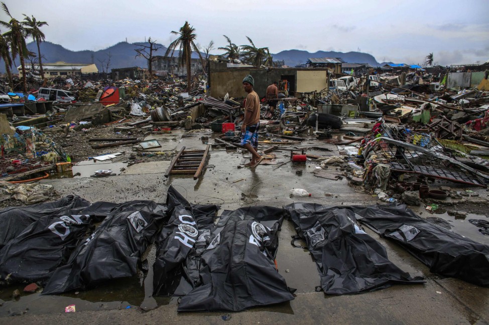 People walk past body bags in Tacloban