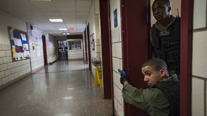 Marine Corps Police officers cover a hallway during a training exercise to respond to a shooting at Quantico Middle High School in Quantico