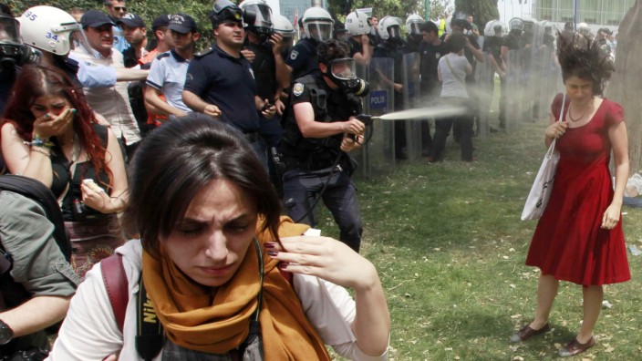 Turkish riot policeman uses tear gas during a protest in central Istanbul