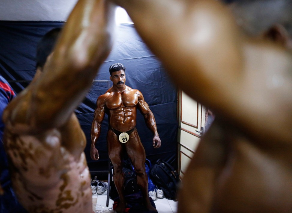 Competitors have tanning lotion applied on their bodies during a bodybuilding competition in Mumbai