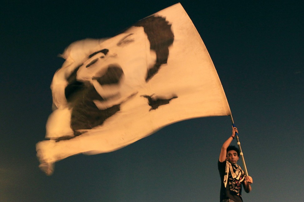 An anti-government protester waves a flag with a picture of youth activist Salah, during a rally against a new law restricting demonstrations, in Cairo