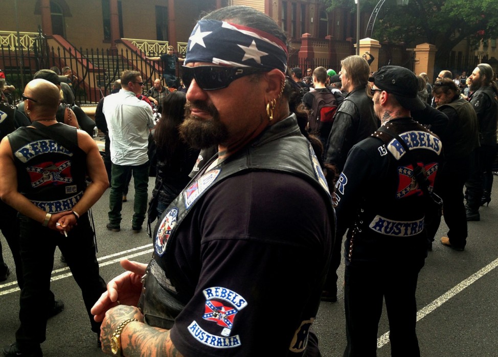 Members of the Rebels motorcycle club stand with recreational motorbike riders outside New South Wales parliament during a protest in Sydney