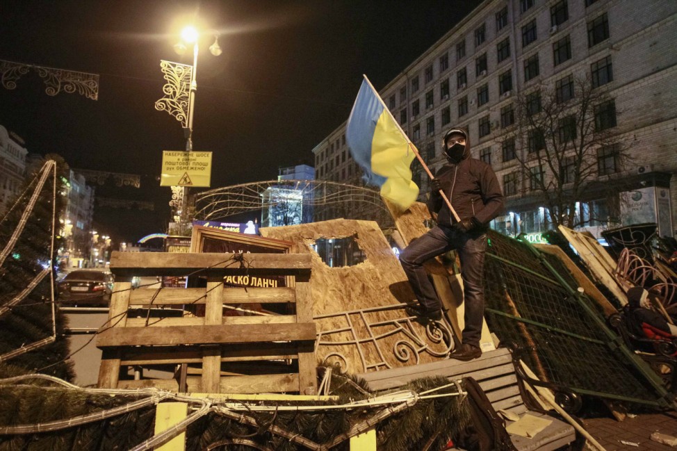 Protester carries a Ukrainian flag as he stands on barricades at Independence Square in Kiev