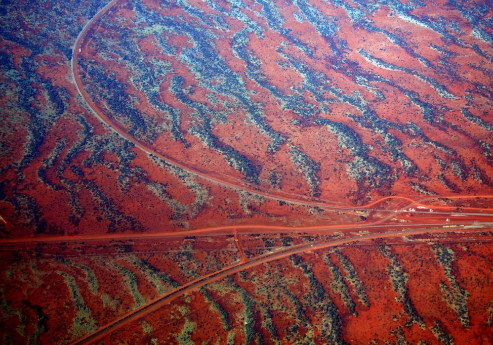 Roads go off in various directions next to sand dunes covered in vegetation in the Pilbara region of Western Australia