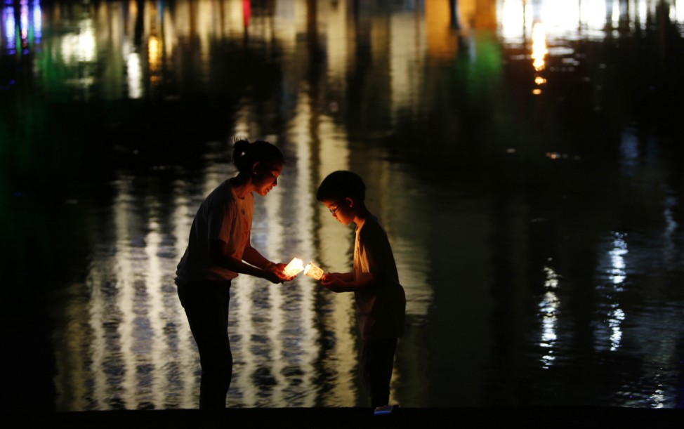 A mother and her son hold candles during an event titled ' A Silent Walk in the Night' in Kuala Lumpur