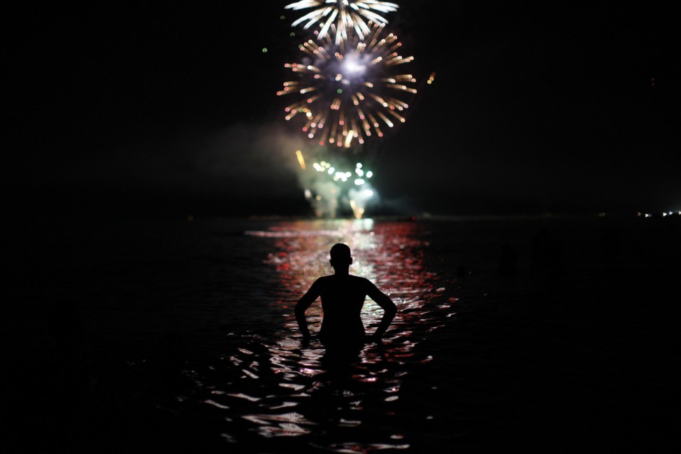 A man watches fireworks as he takes a bath in the Mediterranean Sea on San Juan's night in Malaga