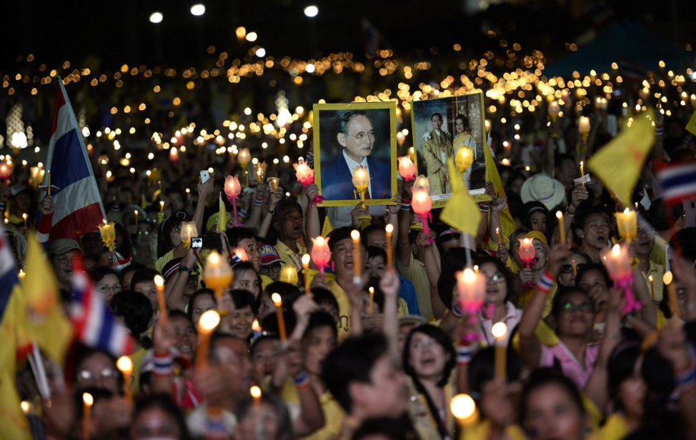 Anti-government protesters hold candles as they take part in birthday celebrations for Thailand's revered King Bhumibol Adulyadej, at the occupied Government buildings in Bangkok