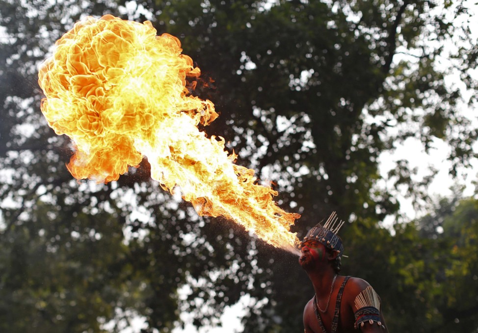 A performer blows fire from his mouth as he performs outside the headquarters of BJP during the celebrations in New Delhi