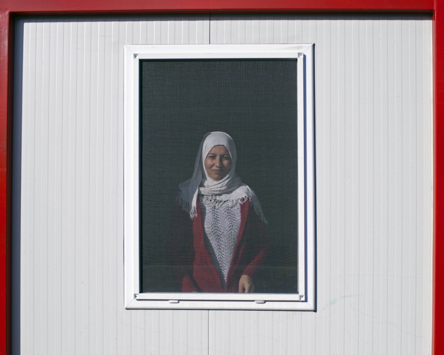 A Syrian woman looks out of the window of a container at a refugee camp in Harmanli