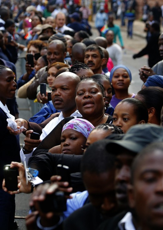 People watch and hold up their mobile phones as the hearse carrying the coffin of former South African President Nelson Mandela travels through a street in Pretoria