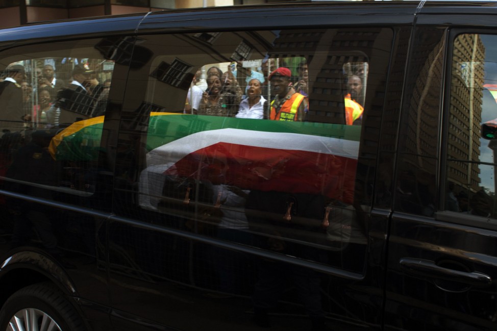 People react as the cortege carrying the coffin of former South African President Nelson Mandela passes through the city centre of Pretoria, on its way to the Union Buildings