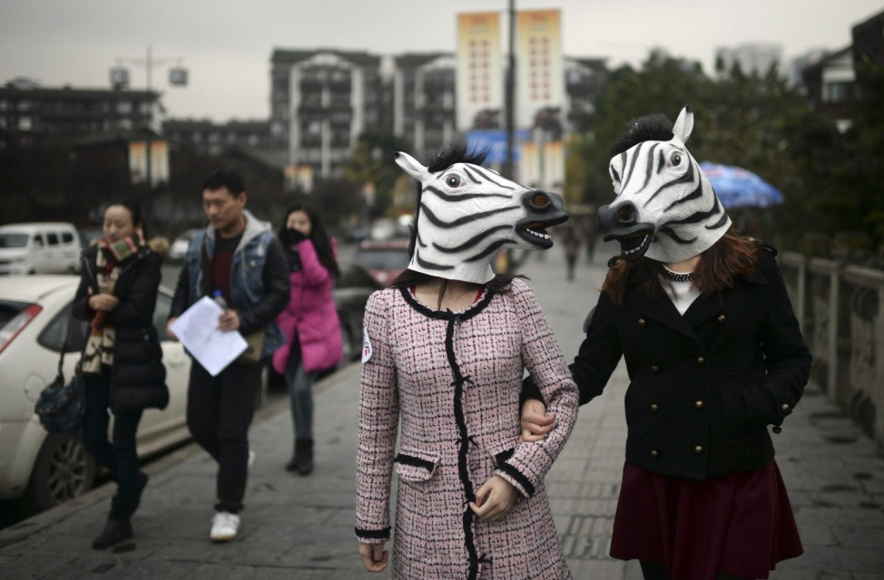 Participants wearing zebra head masks wander down a street as part of an artistic performance in Chongqing