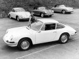 Eine Werbung für einen Porsche 911, dahinter sind drei Porsche 356 platziert.