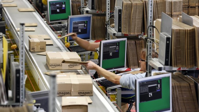 Workers pack boxes at Amazon's logistics centre in Graben