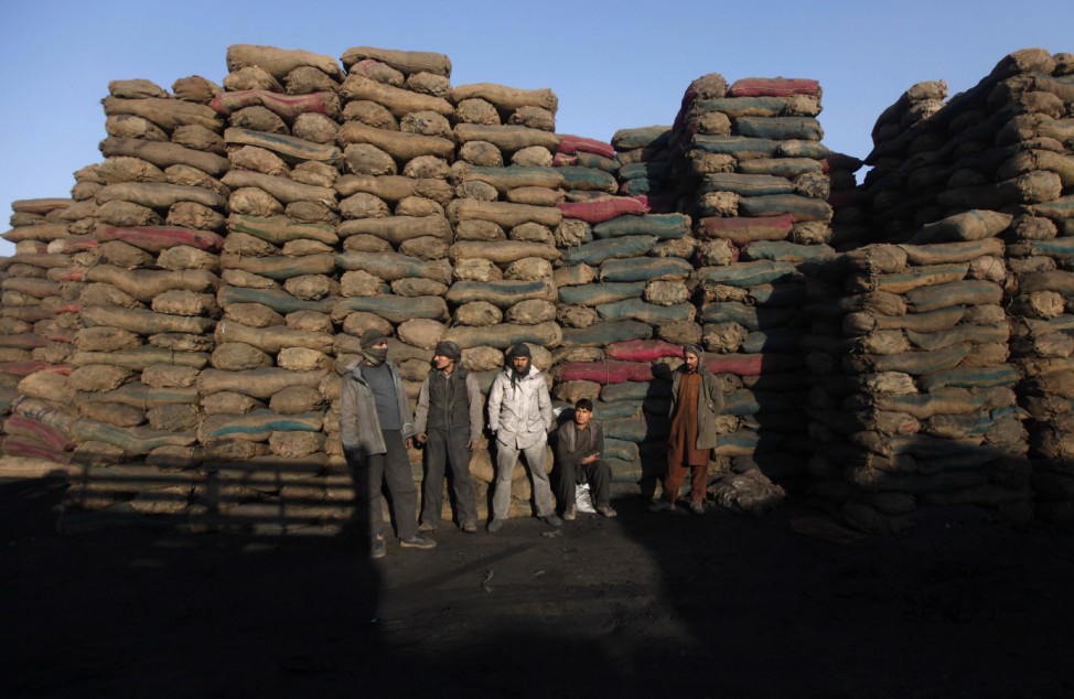 Workers stand at a coal dump site while waiting for customers in Kabul