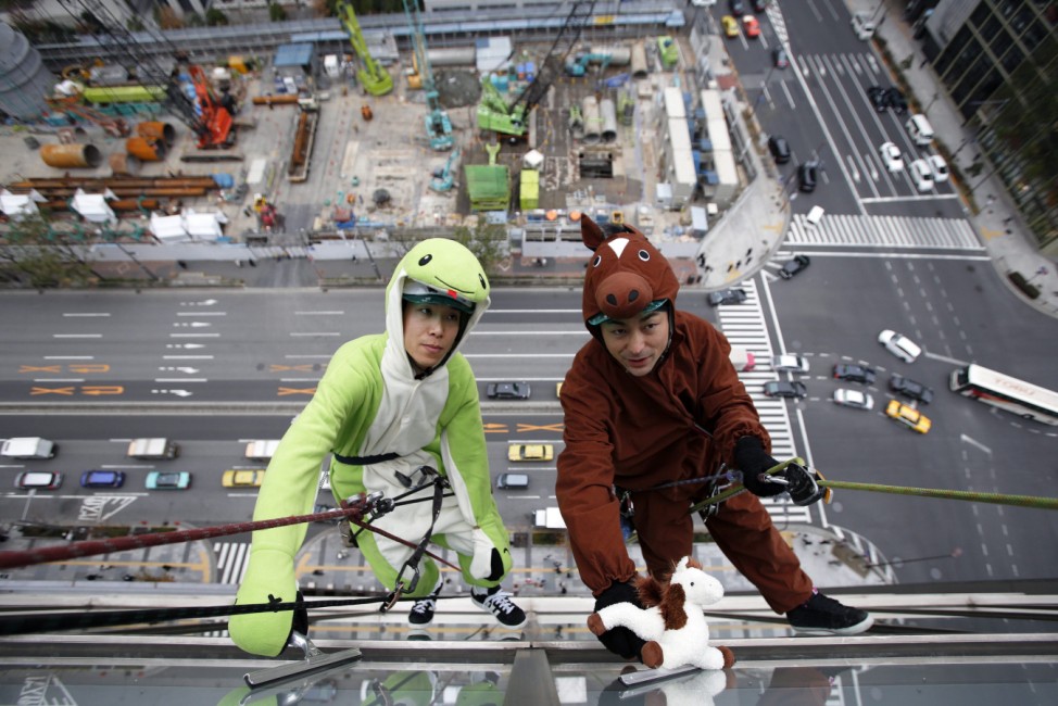 Window cleaners in costumes of snake and horse wipe windows of hi